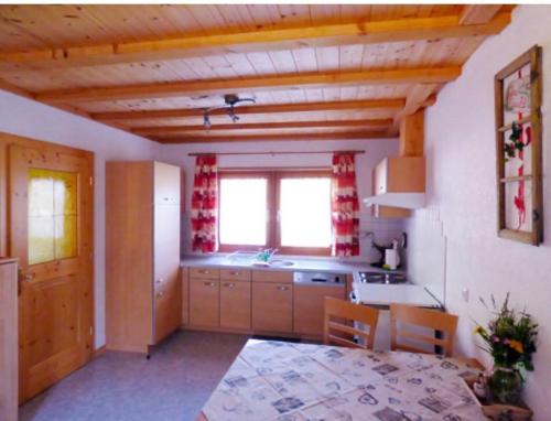 una cucina con soffitti in legno, tavolo e sedie di Egghof a Prato allo Stelvio