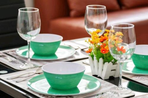 a table with green plates and wine glasses and flowers at Tizapán 2 Beautiful apartment with patio 1BE/1BA in Mexico City