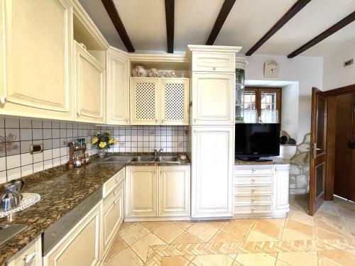 a kitchen with white cabinets and a sink at Mazzetti Country House-Vita in campagna con giardino in Vimignano