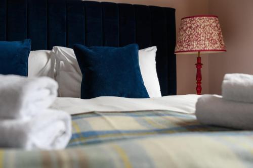 a bed with blue and white pillows and a lamp at Queen Charlotte Guesthouse in Edinburgh