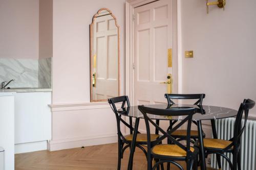 a table with four chairs in a kitchen with a door at Queen Charlotte Guesthouse in Edinburgh