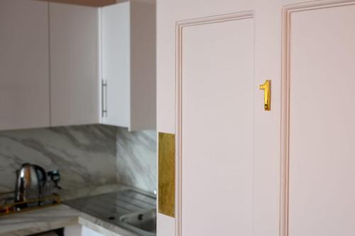 a white kitchen with a door with the number one on it at Queen Charlotte Guesthouse in Edinburgh