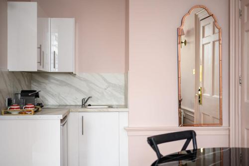 a kitchen with white cabinets and a black chair at Queen Charlotte Guesthouse in Edinburgh