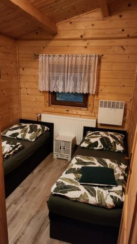 a bedroom with two beds in a log cabin at Domek drewniany in Piekielnik