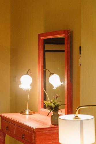two lights sitting on a table with a mirror at Bhirom at Baan Thongjaya in Ban Fon