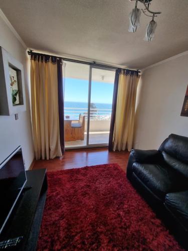a living room with a couch and a view of the ocean at Departamento Frente Playa las Torpederas in Valparaíso