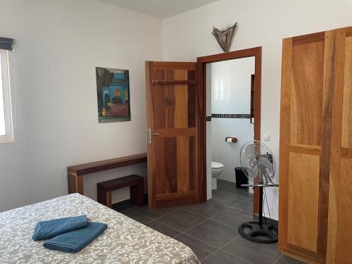 a bedroom with a bed and a bathroom with a fan at Villa Sol e Mar - Vila do Maio - Ponta Preta in Vila do Maio