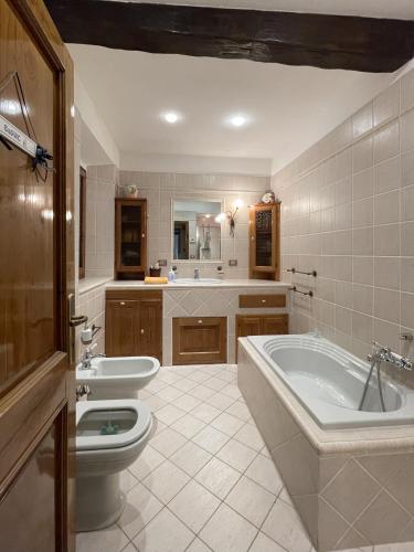 a bathroom with a tub and a toilet and a sink at Mazzetti Country House-Vita in campagna con giardino in Vimignano