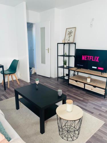 uma sala de estar com uma mesa preta e uma televisão em Appartement confortable aux portes de Paris em Charenton-le-Pont