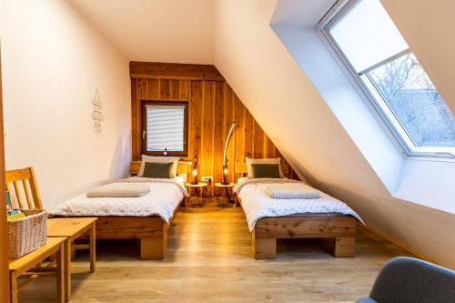 a attic room with two beds and a window at Apartmaji pri Dravi in Podvelka