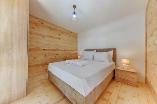 1 dormitorio con 1 cama con pared de madera en Family Bungalows en Ulcinj