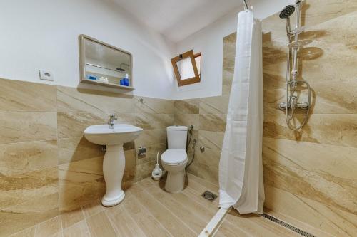 y baño con aseo, lavabo y ducha. en Family Bungalows en Ulcinj