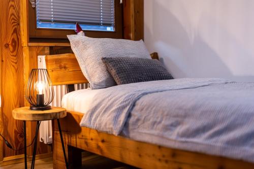 a bed with a blue blanket and a lamp on a table at Apartmaji pri Dravi in Podvelka