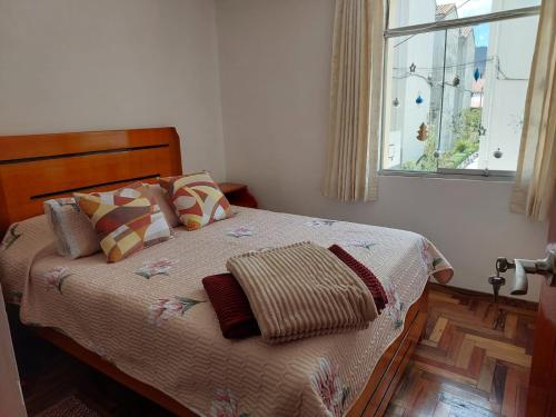 a bed in a bedroom with a window and a bedspread at Mandalas Cusco in Cusco