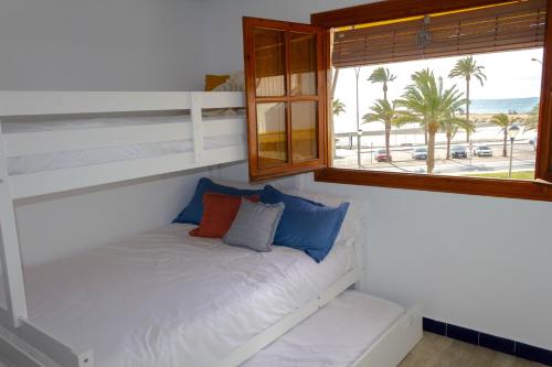 Łóżko w pokoju z oknem z widokiem na plażę w obiekcie BRISAS VARADERO w mieście Santa Pola