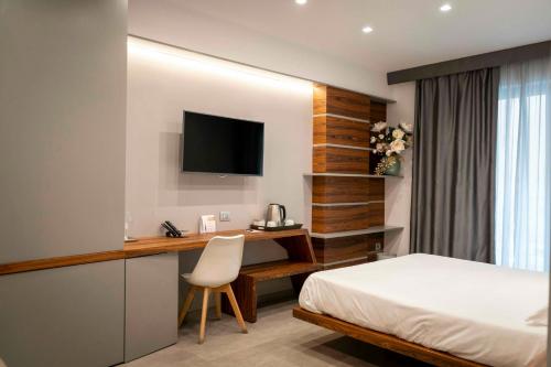 a bedroom with a bed and a desk with a television at B&B Rakel Home in Milazzo