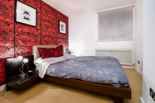 a bedroom with a bed with a red wall at 2BR flat next to London Eye on lower marsh 96A in London