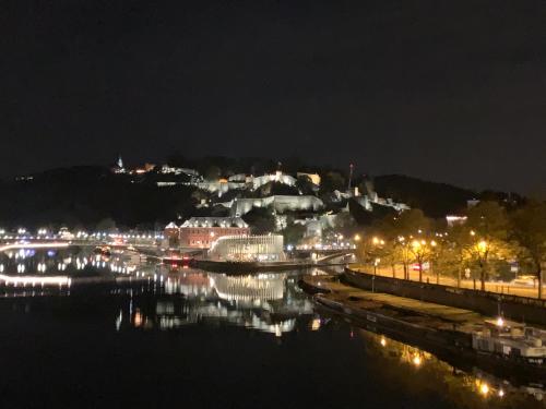uma cidade iluminada à noite com um corpo de água em Studio vue sur Meuse em Namur