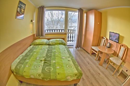 a bedroom with a bed and a table and a window at Willa Izery in Szklarska Poręba