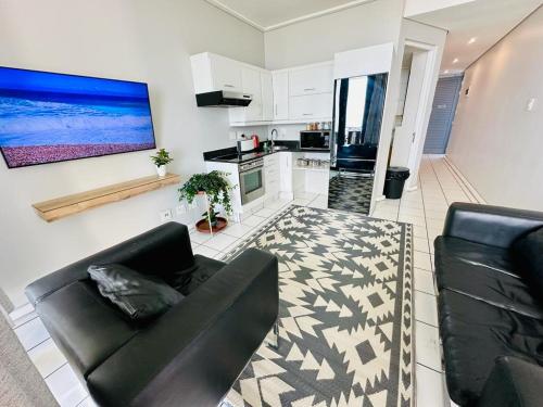 a living room with a black couch and a kitchen at The Waves 905 Quayside Point in Durban
