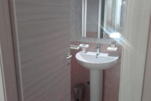 W łazience znajduje się biała umywalka i lustro. w obiekcie camera b&b w mieście Parma