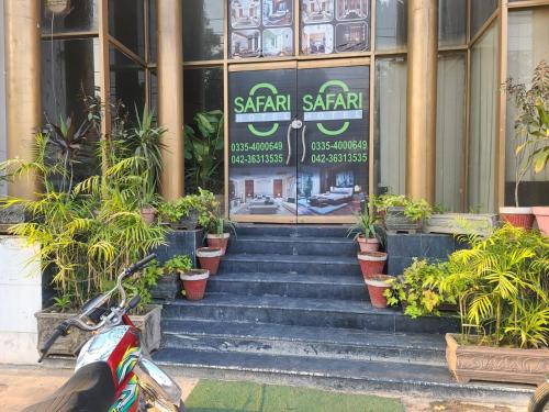 Safari Hotel في لاهور: دراجة نارية متوقفة أمام مبنى به نباتات الفخار
