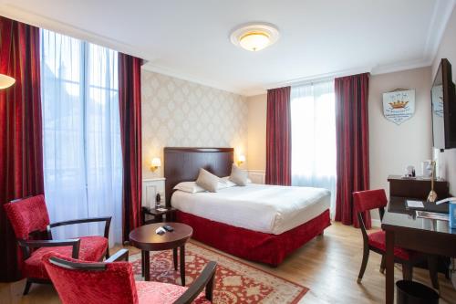 ブールジュにあるBest Western Plus Hôtel D'Angleterreのベッド、デスク、椅子が備わるホテルルームです。