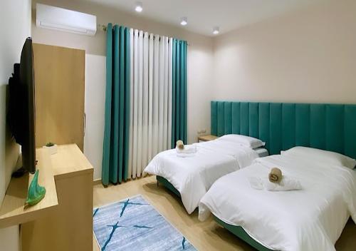 2 łóżka w pokoju z zielonymi zasłonami w obiekcie Hotel Krial w mieście Berat