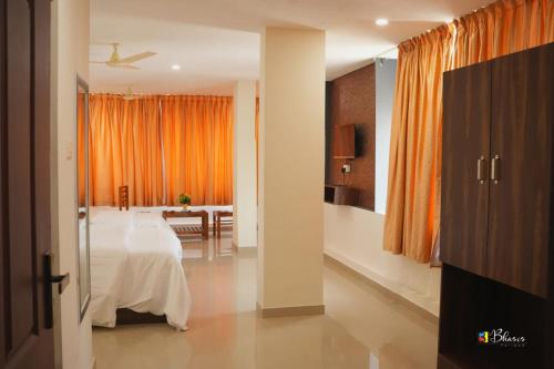 a bedroom with a bed and an orange curtain at GLANCY'S GUEST HOUSE in Haripād