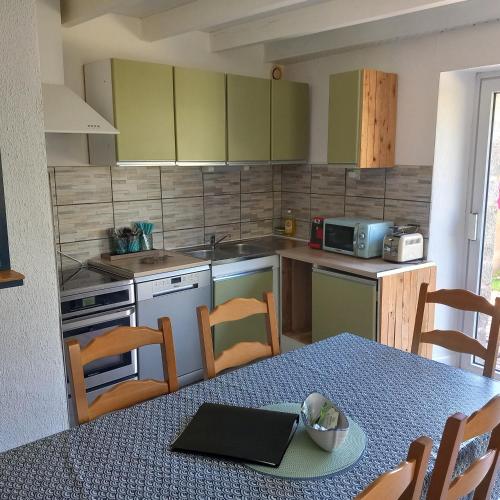 a kitchen with a table and chairs and a microwave at Gite Les Sables Blancs in Plobannalec-Lesconil