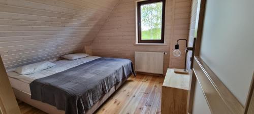 a small bedroom with a bed in a wooden room at Domek przy Polnej Drodze in Langendorf