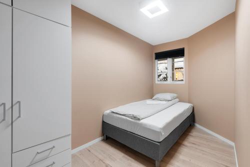 a small bedroom with a bed and a window at Cozy new apartment in Kristiansand