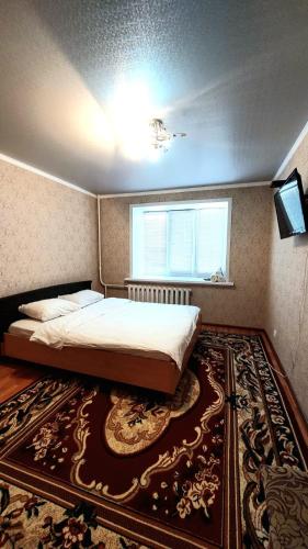 1 dormitorio con cama, ventana y alfombra en Аэропорт Астана 5 минут юг1 582 en Prigorodnyy