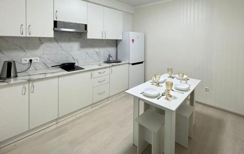 アルマトイにあるNureke Apartmentsの白いキッチン(テーブル、冷蔵庫付)