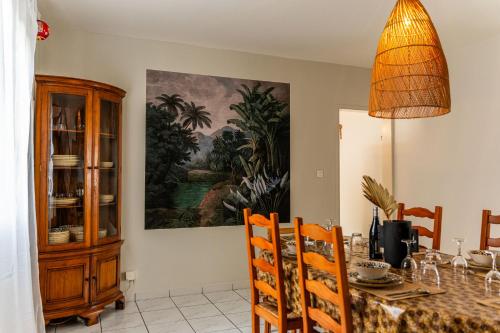 a dining room with a table and a painting on the wall at Villa Marinia 3*: Charme Créole in Saint-Denis