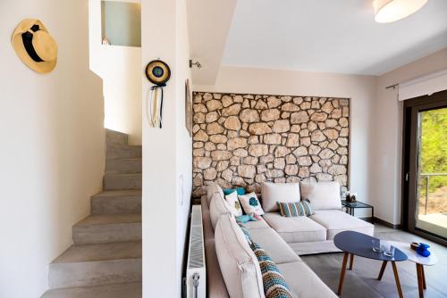 a living room with a couch and a stone wall at Aegean View in Vasiliká
