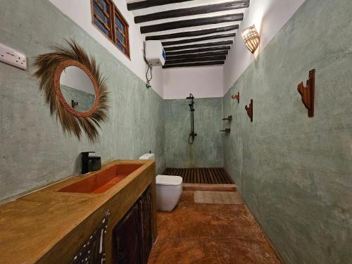 a bathroom with a sink and a toilet and a mirror at Karibu Maisha in Kizimkazi