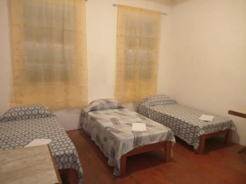 Habitación con 2 camas y mesa. en Pousada Inaya, en Petrópolis