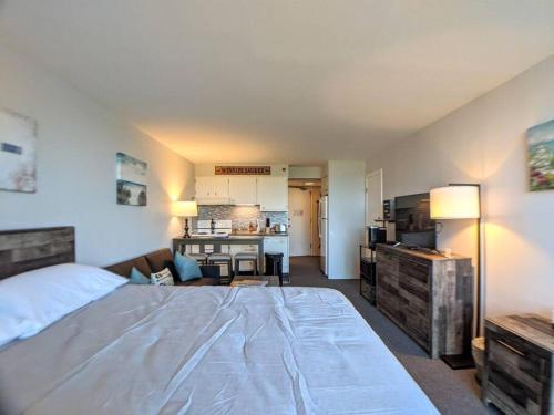 a bedroom with a large bed and a kitchen at Cute Cedar Lodge Studio with Balcony & Lake Views! in Laconia