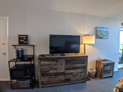 a living room with a large television on a dresser at Cute Cedar Lodge Studio with Balcony & Lake Views! in Laconia