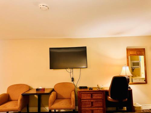a hotel room with two chairs and a flat screen tv at Fundy Line Motel in Miramichi