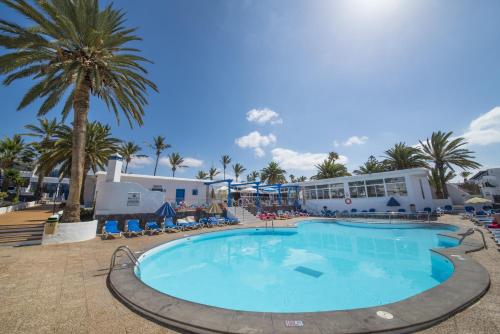 una gran piscina con palmeras y un edificio en Apartamentos Jable Bermudas, en Puerto del Carmen