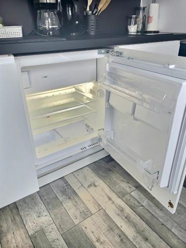 an empty refrigerator with its door open in a kitchen at Le Jard in Châlons-en-Champagne