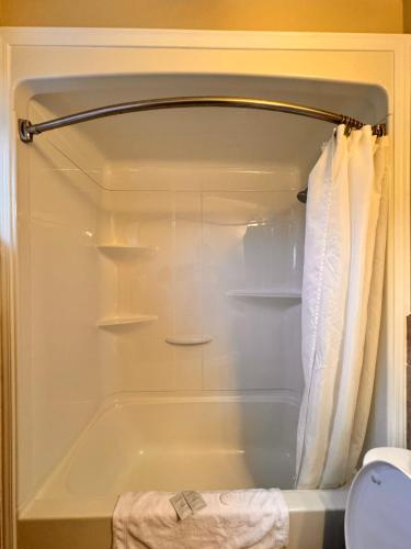uma casa de banho com um chuveiro e uma banheira em Fundy Line Motel em Miramichi