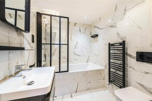 a bathroom with a sink and a tub and a toilet at Fulham Townhouse, 2 Baths, Parking, Breakfast in London