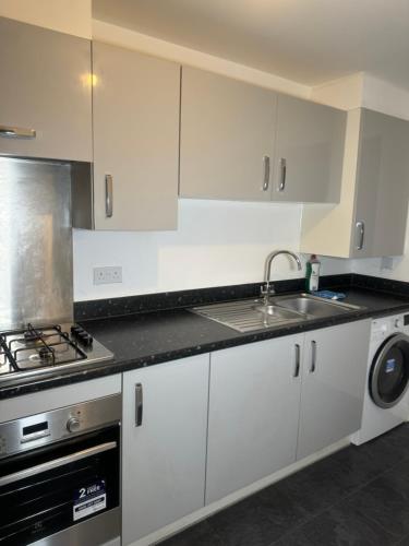 a kitchen with white cabinets and a sink and a stove at Amity Luxury Home Dartford in Kent