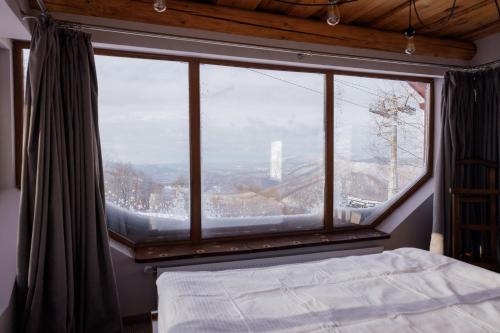 a bedroom with a large window with a mountain view at Hygge House in Vyshka