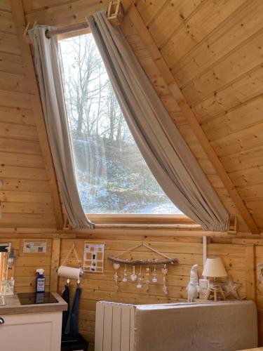 - une grande fenêtre dans une chambre avec plafond dans l'établissement Cabane, Kota Désiré, à Saint-Dié-des-Vosges