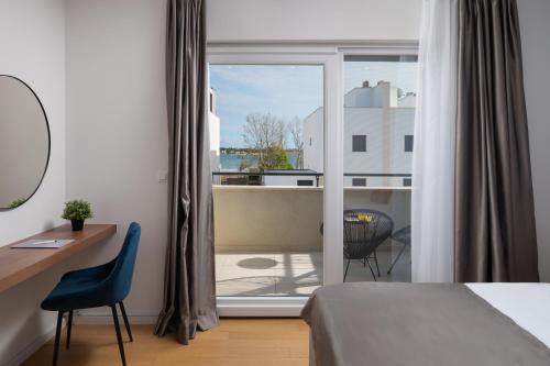 a bedroom with a bed and a desk and a window at Villa Roca with heated pool and sauna in Privlaka