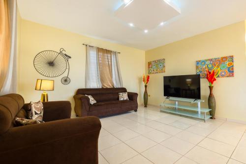 a living room with two couches and a flat screen tv at Colinas del Atlantico Vacational House 2nd Floor in Isabela